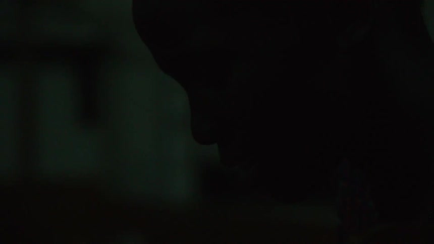 A person is leaning forward in a dark room