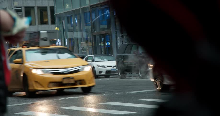 Cars drive on a city street while it rains
