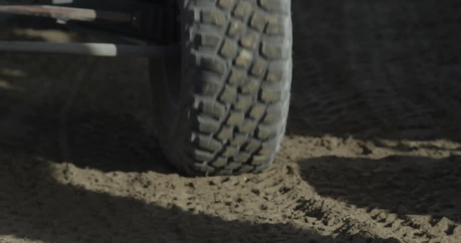 A dune buggy's tire as it moves over sand