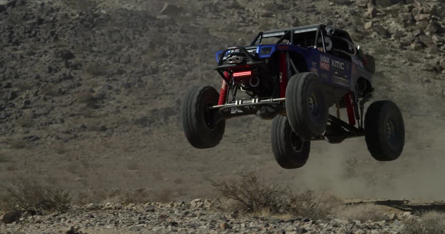An off road vehicle jumping up a hill