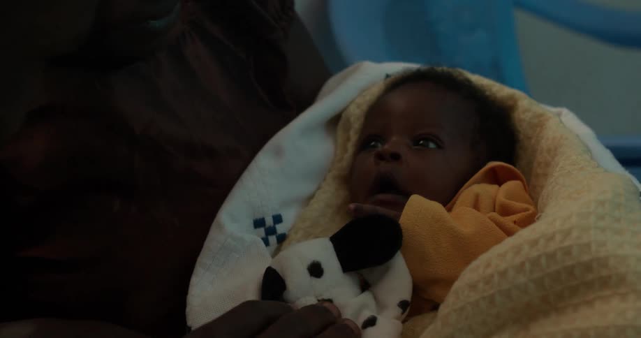 A man and woman sit with a newborn baby