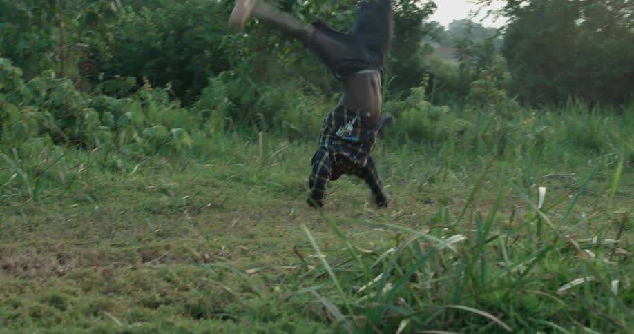 A young boy does a cartwheel and flip in the grass