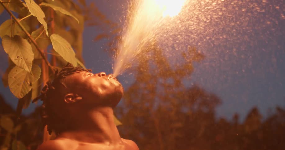 A man blows on a torch and a flame erupts in the air