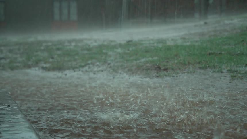 Rain pours and puddles near a concrete pad
