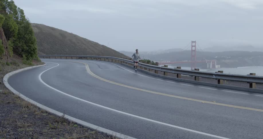 A man jogs down a wet road in the hills