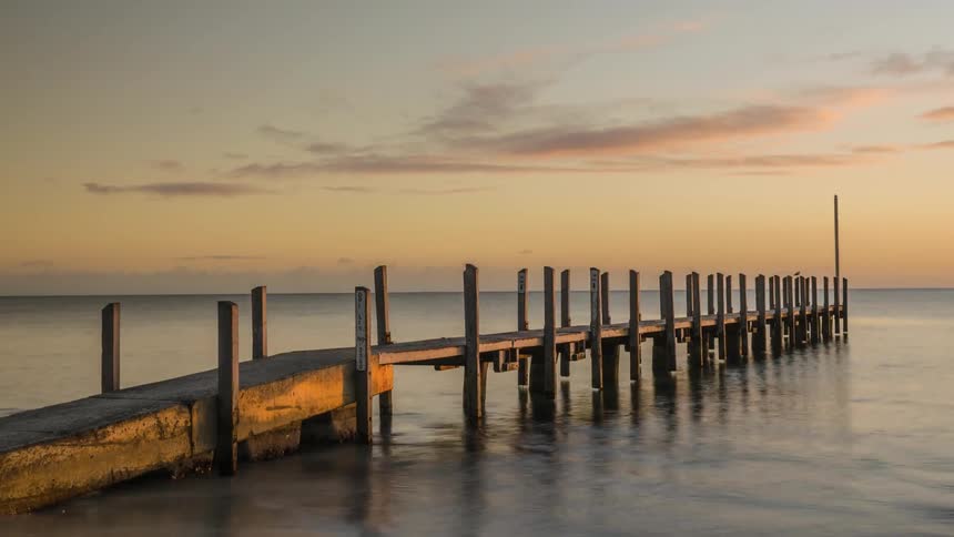 golden sunlight striking a pier as the sun rises