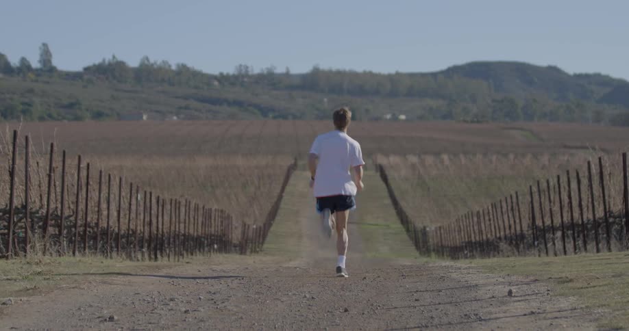 A man is running on a mud path on a sunny day