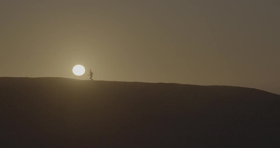 A man is running across the horizon just as the sun is rising