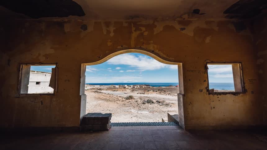 An old stone building is being walked through towards the exit into a desert