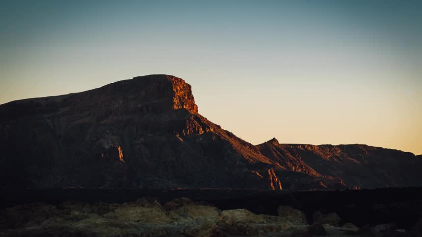 The sun sets near rock formations in the desert