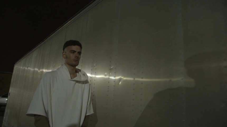 Someone is a large white shirt is walking towards flashing lights