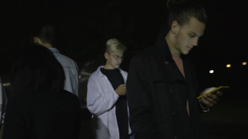 A group of young people stare at their phones