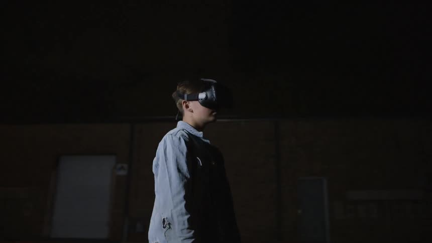 A kid with a vr device is standing in a parking lot with a strobe light flashing