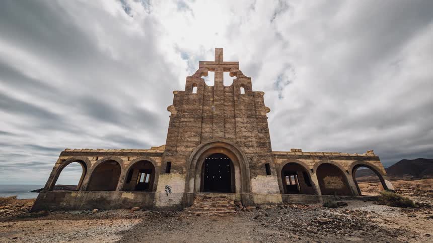 A cross statue sits atop an abandoned church