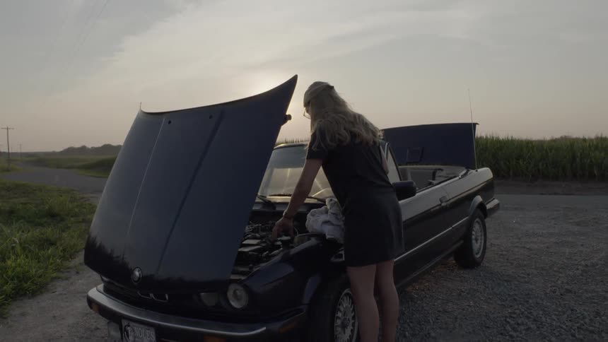 A woman is working on her convertible