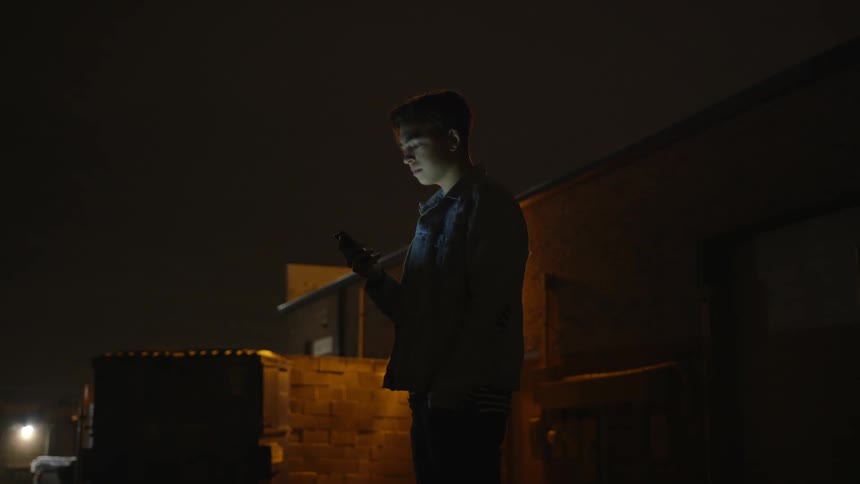 A person is standing outside looking at their phone