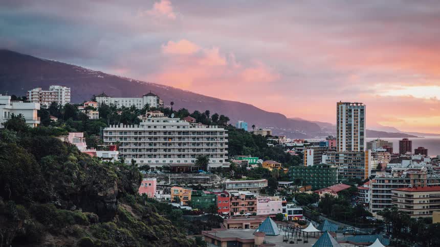 The sun sets behind an oceanside city