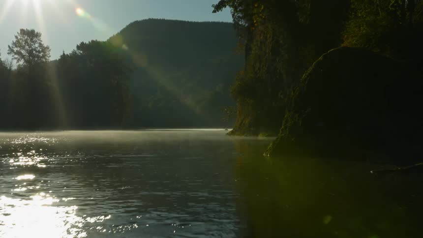 A drone is flying over a rock covered beach and a small river