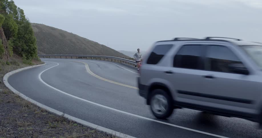 A man jogs on a windy road