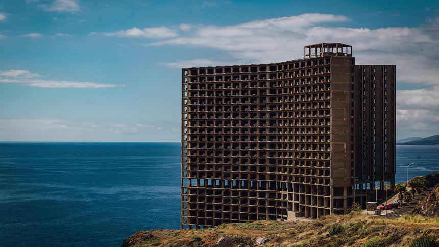 Tall structure sits next to the water under a blue sky