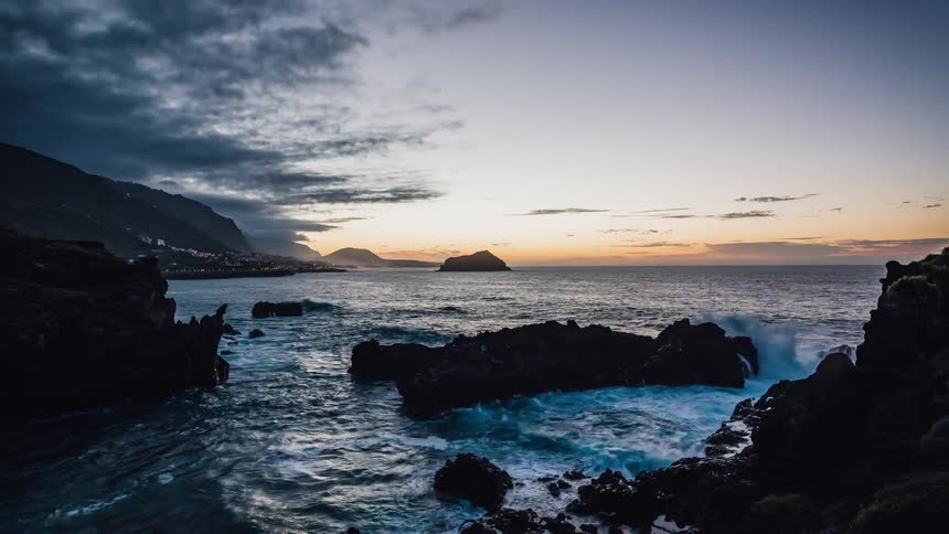 Water flows around the rocks under a cloudy sky