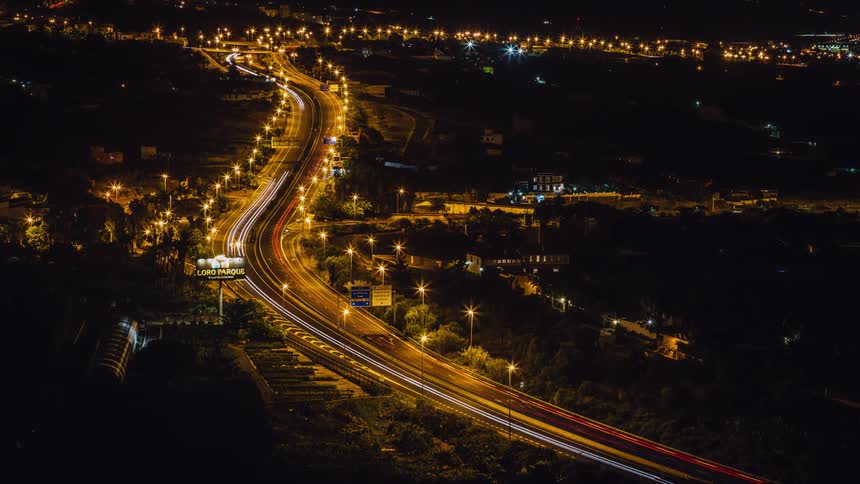 Vehicle lights are casting long trails as they travel on a freeway