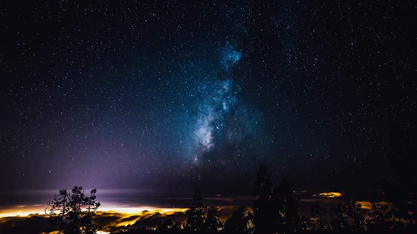 Waves crash into shore under a night sky