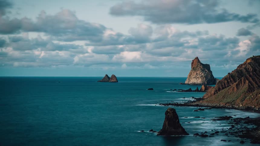 Clouds pass over a rocky coastline during the day