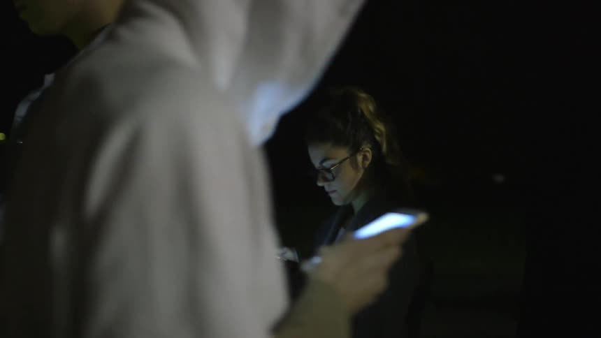 A group of people looking at their cell phones at night