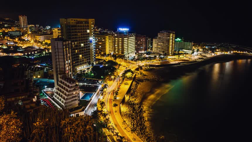 Cars travel along the road of the city by the shore at night