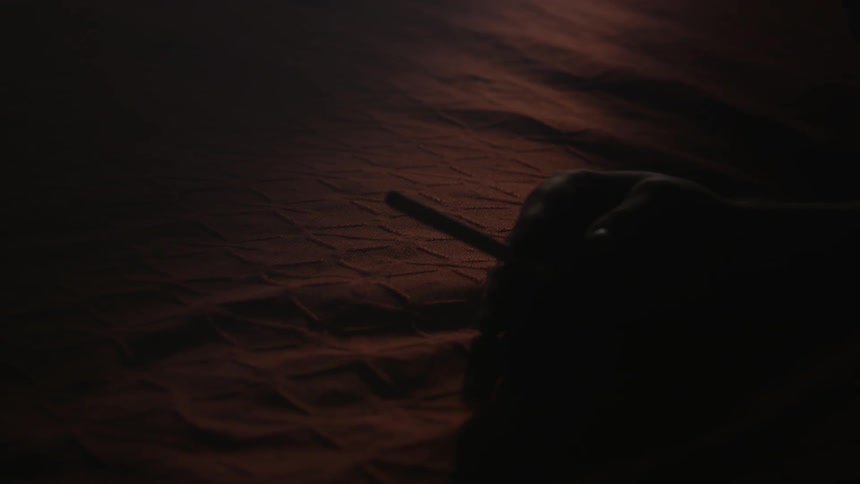 Hand holding a cigarette in a dimly lit room