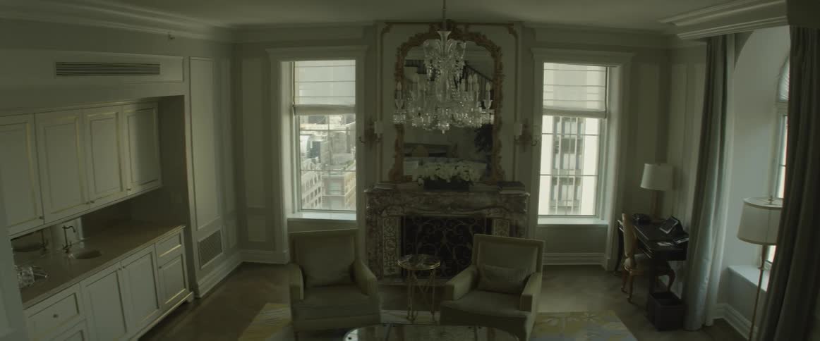Two chairs in front of a fireplace with a chandelier overhead