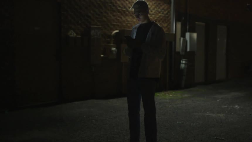 A person is standing in the road looking at their phone