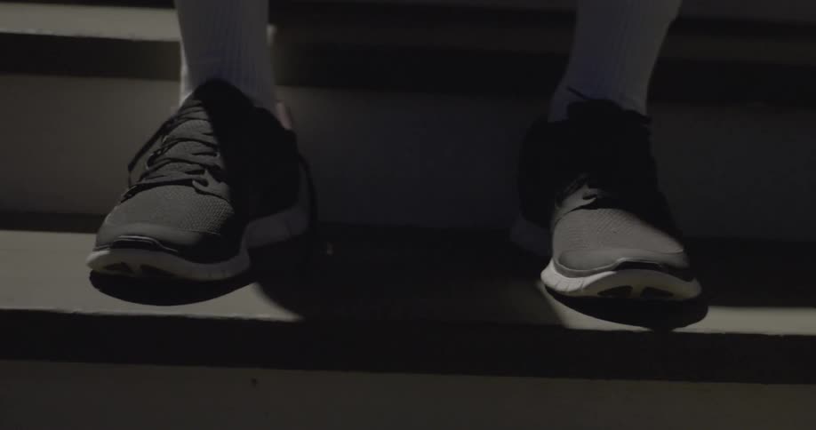 The shoes of a person sitting on a staircase