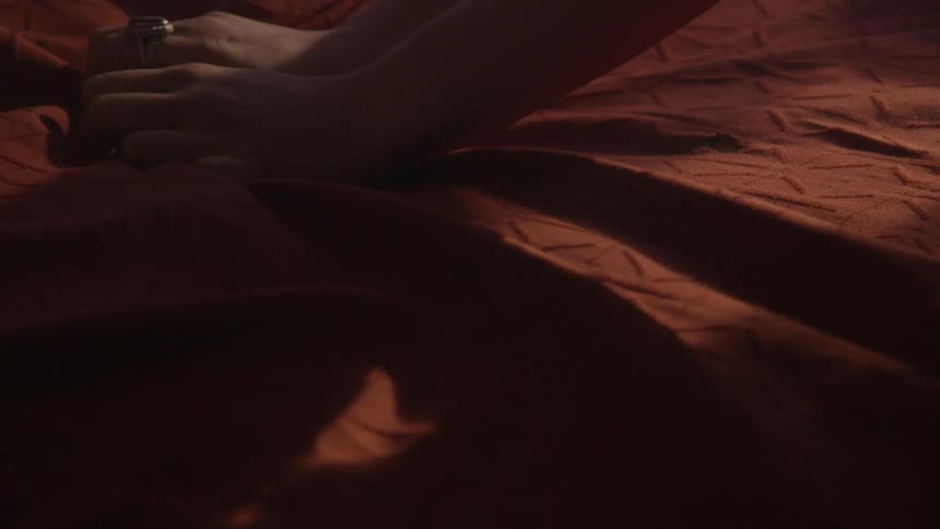 A woman rubs and feels on red sheets
