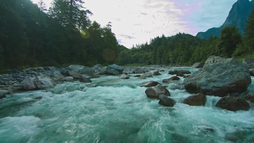 A drone is filming low over running rapids of a stream