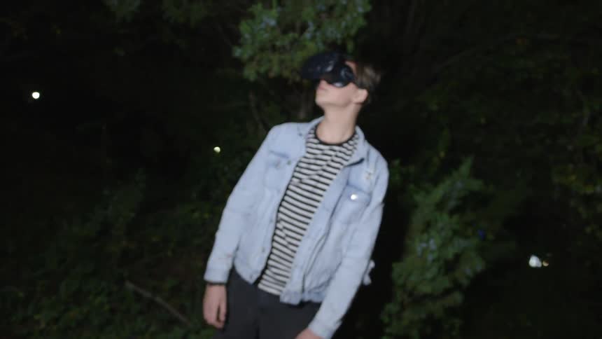 A man wearing a vr headset looks around outside