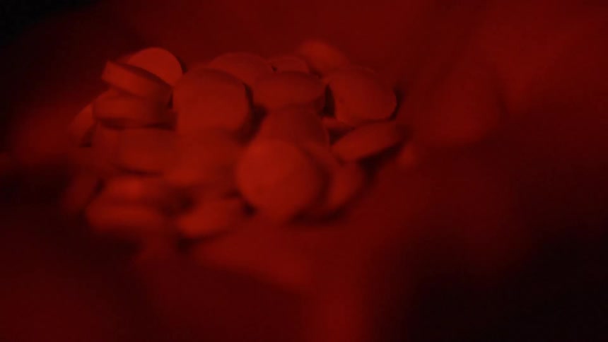 A person pours a bunch of pills into their hand