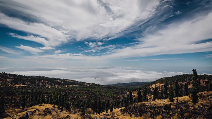 Clouds and fog move across a hilly landscape during the day
