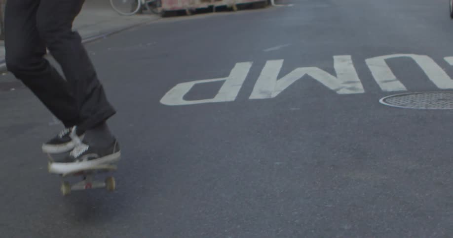 A boy performs a skateboard trick in the street