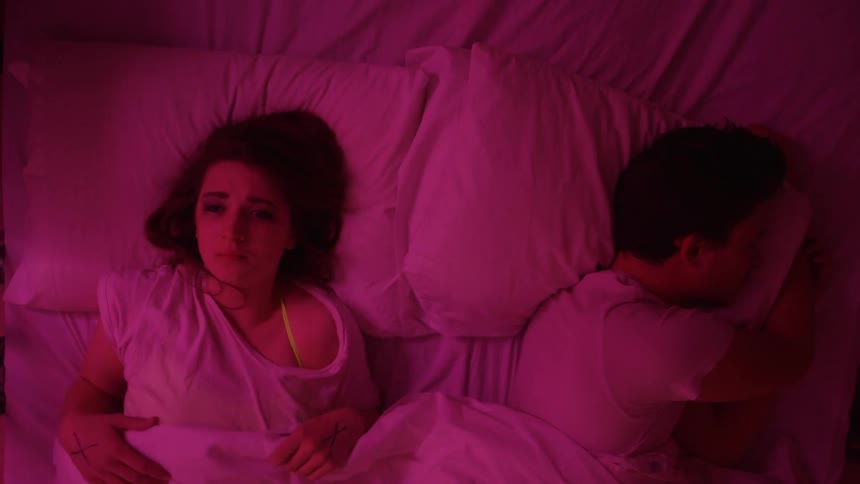 A woman awake in bed with a man