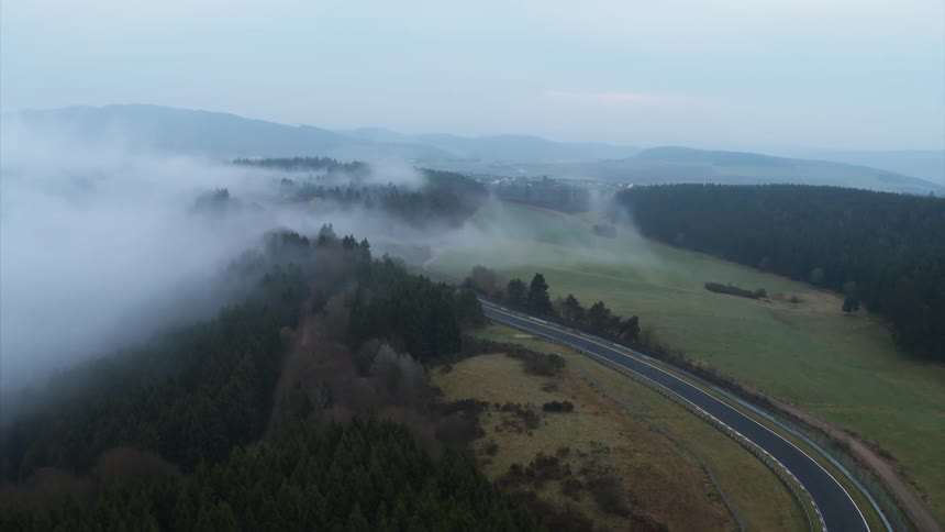 A fog bank rolls over a road in a rural area