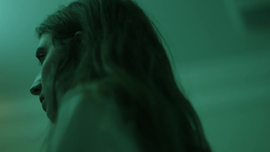 A woman stands in a green tinted room