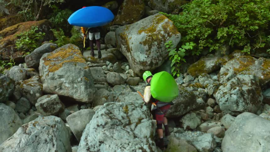 Two kayaks are being walked up a rocky cliff