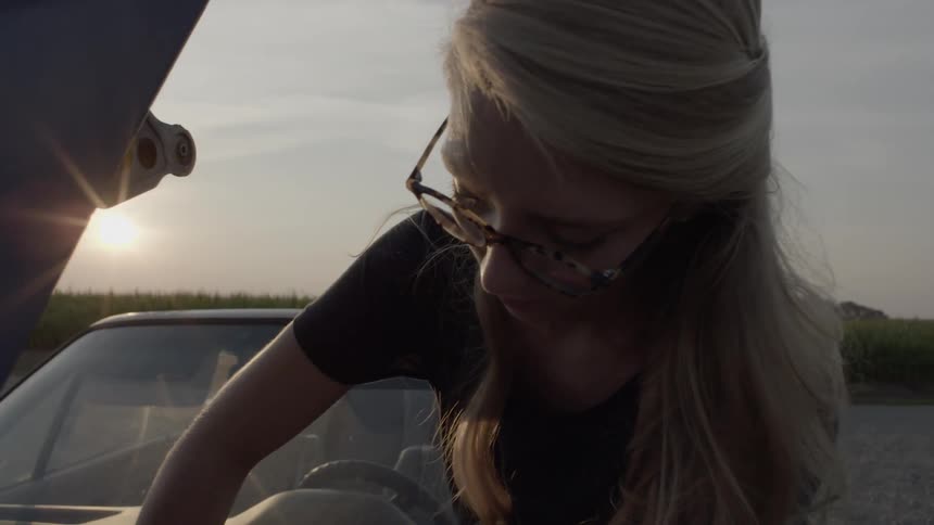 A woman is pouring fluid into her car's engine