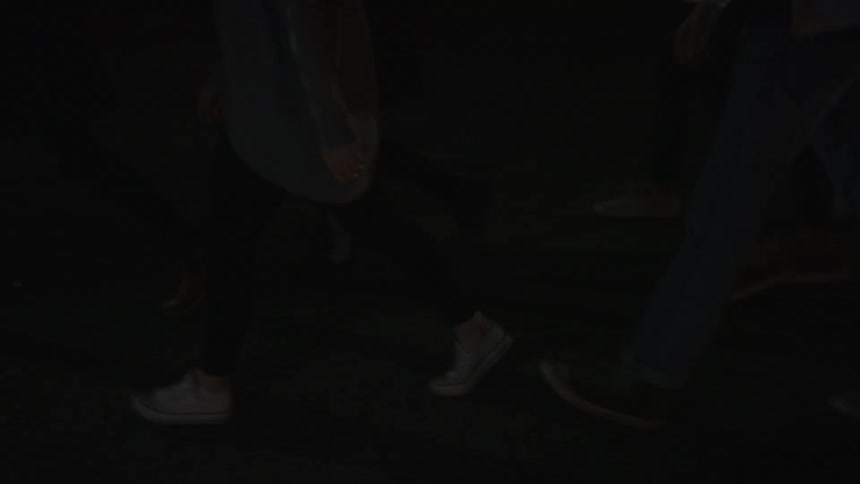 A group of young adults walking down the street at night