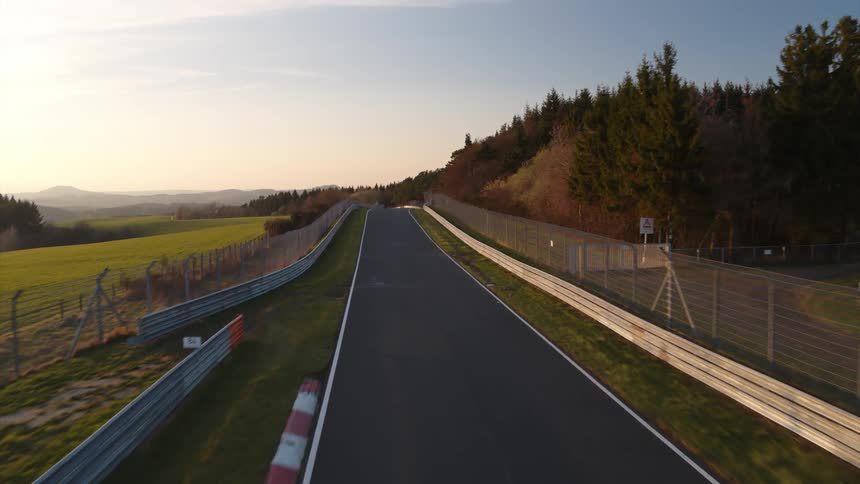 A fenced in road near some woods