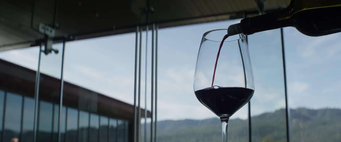 Wine is being poured into a glass with a big window in the background