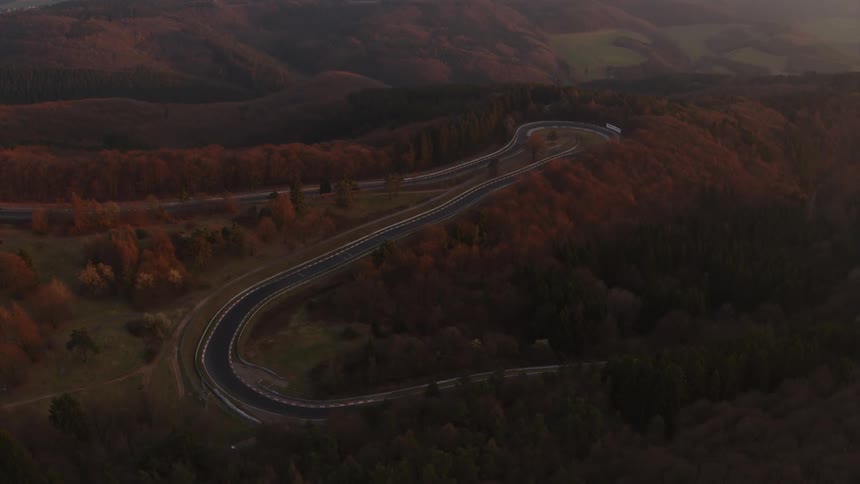 A road winds through a forest on a rural hilltop