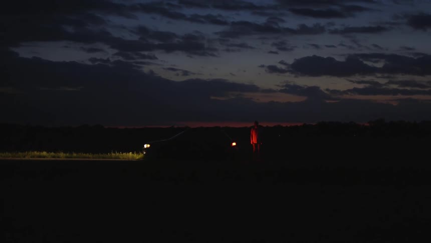 A parked car sits with its headlights on